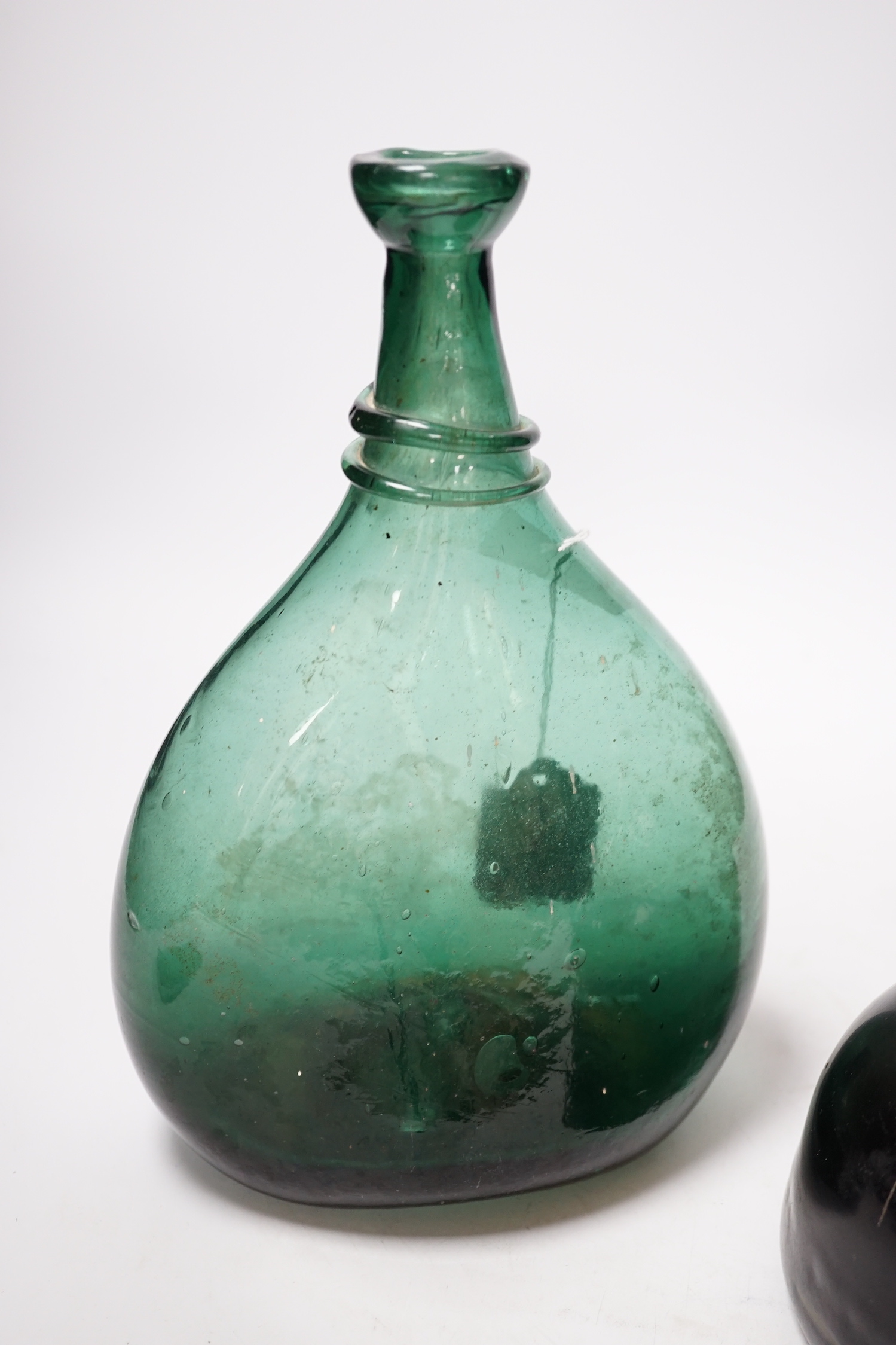 An 18th century black glass mallet form bottle with neck rim, 17cm and an 18th century Persian green glass flask, 27cm